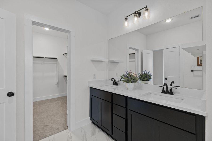 Great view of the beautiful primary bathroom with two separate sinks and a large walk in closet.