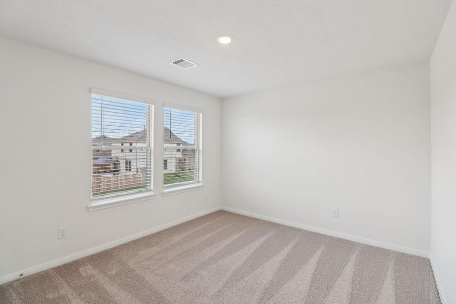 This secondary bedroom offers comfort and style with plush carpeting, neutral paint tones, recessed lighting, large windows with blinds, and a generously sized closet.