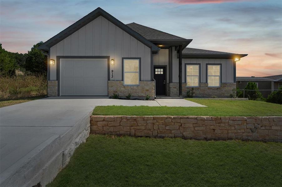 View of front of home featuring stone siding, board and batten siding, driveway, and a garage View of front of home featuring stone siding, board and batten siding, driveway, and a garage