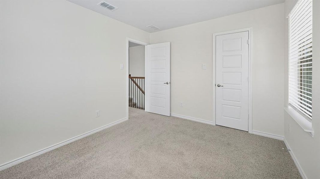 Unfurnished bedroom featuring light colored carpet and baseboards