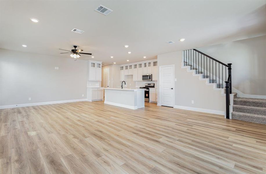 Unfurnished living room with light wood-style flooring, recessed lighting, stairs, and ceiling fan
