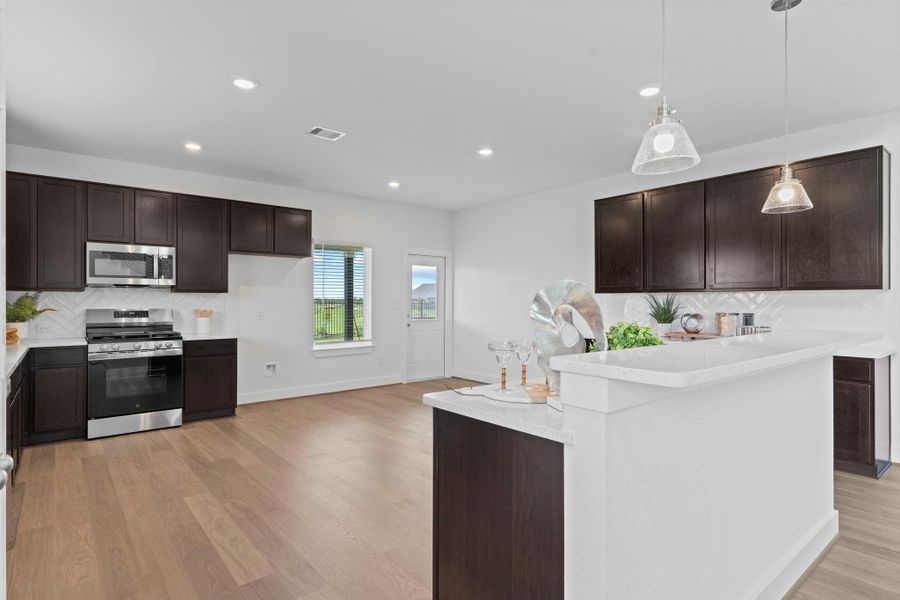 The open layout flows beautifully from the kitchen into the living and dining areas, creating a seamless space for entertaining and daily life—all tied together with woodlike vinyl flooring and recessed lighting. **Image Representative of Plan Only and May Vary as Built**. The open layout flows beautifully from the kitchen into the living and dining areas, creating a seamless space for entertaining and daily life—all tied together with woodlike vinyl flooring and recessed lighting. **Image Representative of Plan Only and May Vary as Built**.