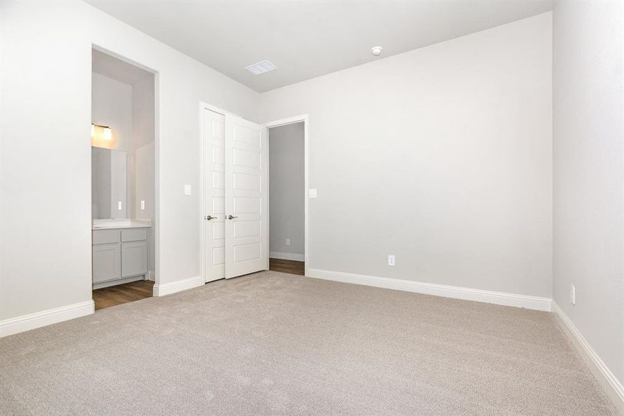Unfurnished bedroom featuring light carpet and ensuite bathroom