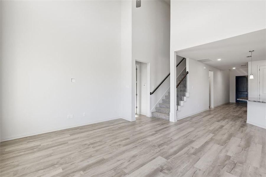 Unfurnished living room featuring a high ceiling, light wood-style floors, and recessed lighting Unfurnished living room featuring a high ceiling, light wood-style floors, and recessed lighting