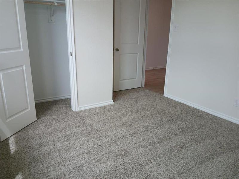 Neutral-toned carpeting extends throughout this interior space, featuring white baseboards and trim Neutral-toned carpeting extends throughout this interior space, featuring white baseboards and trim