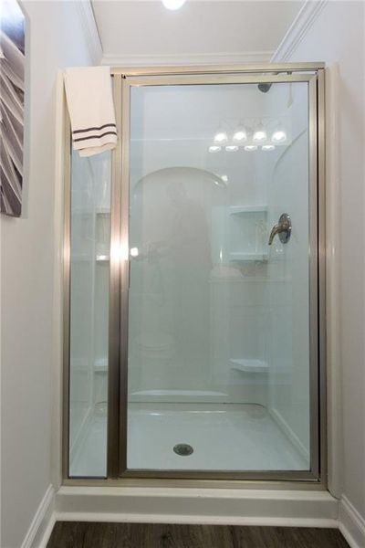 Bathroom with hardwood / wood-style floors, walk in shower, and crown molding