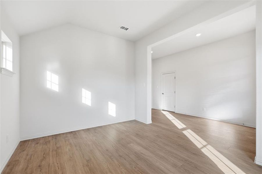 Spare room with light wood-style floors and lofted ceiling Spare room with light wood-style floors and lofted ceiling