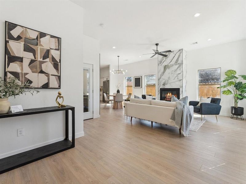 Living room featuring light wood finished floors, a fireplace, baseboards, and recessed lighting