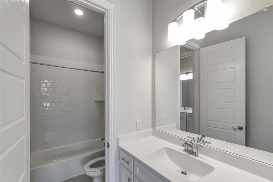 Full bathroom featuring vanity, tiled shower / bath, tile patterned floors, and toilet