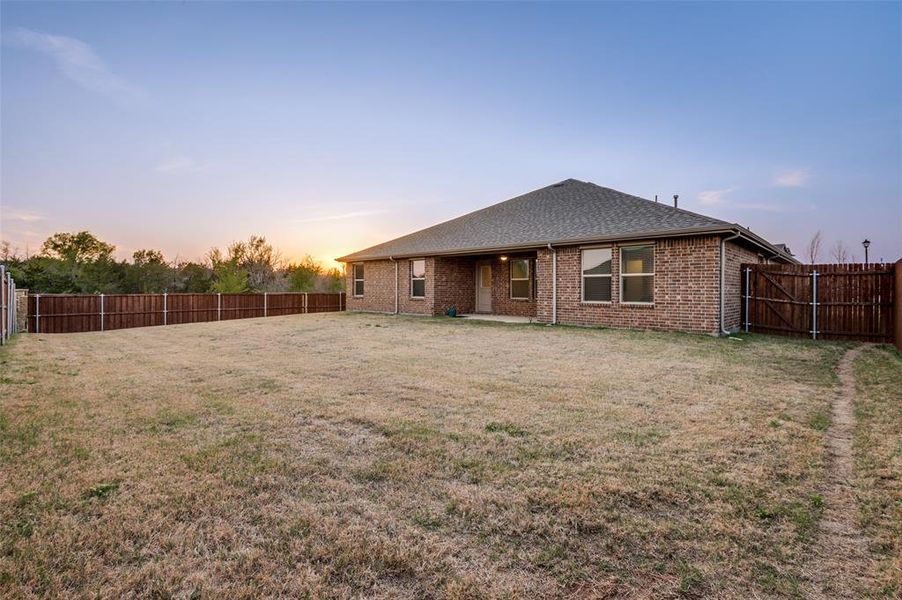 Back of house featuring a patio, brick siding, a fenced backyard, and a gate