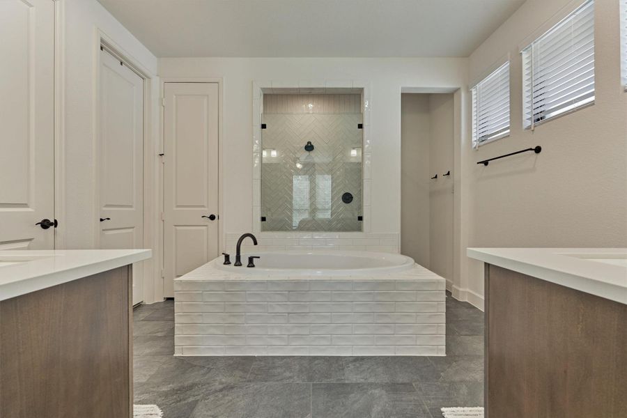 This primary bath offers a serene retreat with its elegant freestanding tub, sleek glass shower, and stylish modern finishes, creating a spa-like experience right at home.