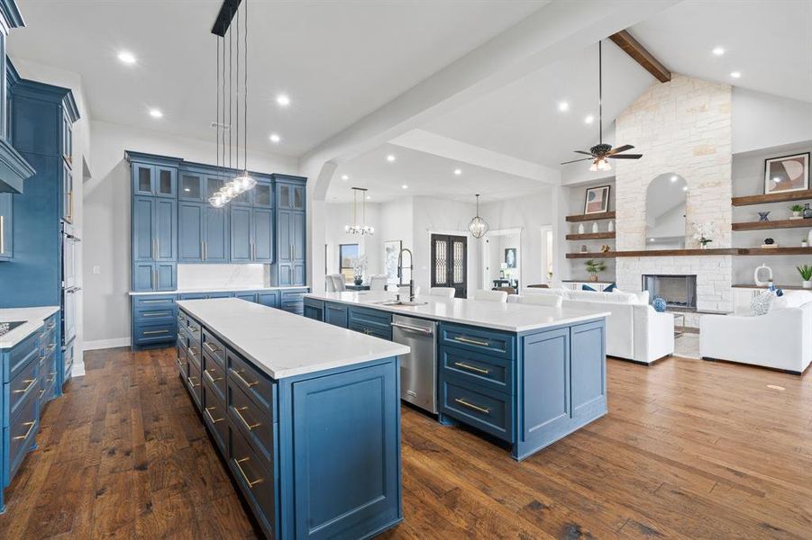 Kitchen featuring stainless steel appliances, sink, beamed ceiling, pendant lighting, and a kitchen island with sink