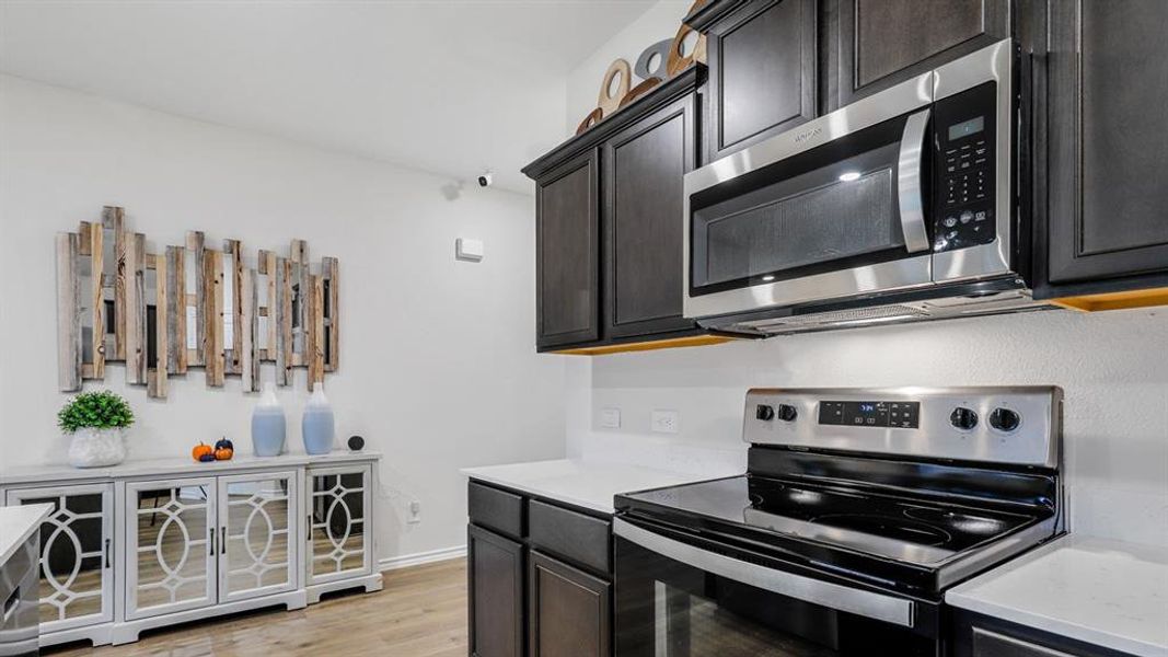 Kitchen featuring stainless steel appliances, light wood-style floors, and light stone countertops Kitchen featuring stainless steel appliances, light wood-style floors, and light stone countertops