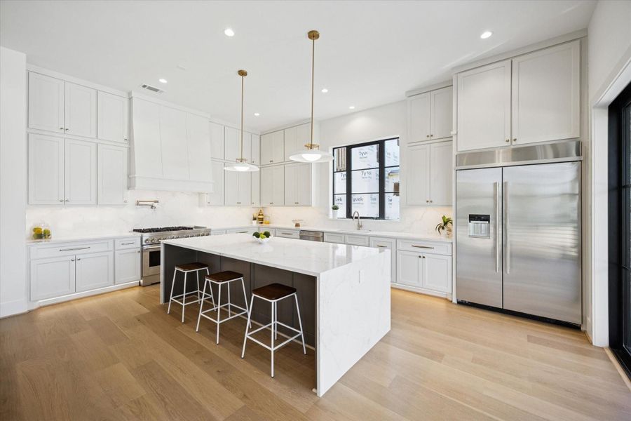 Kitchen - has a gorgous island with double quartz waterfall edge and features commercial style appliances including 48" side-by-side refrigerator.
