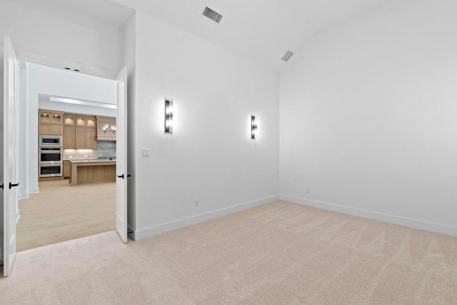 Spare room with light colored carpet and lofted ceiling Spare room with light colored carpet and lofted ceiling