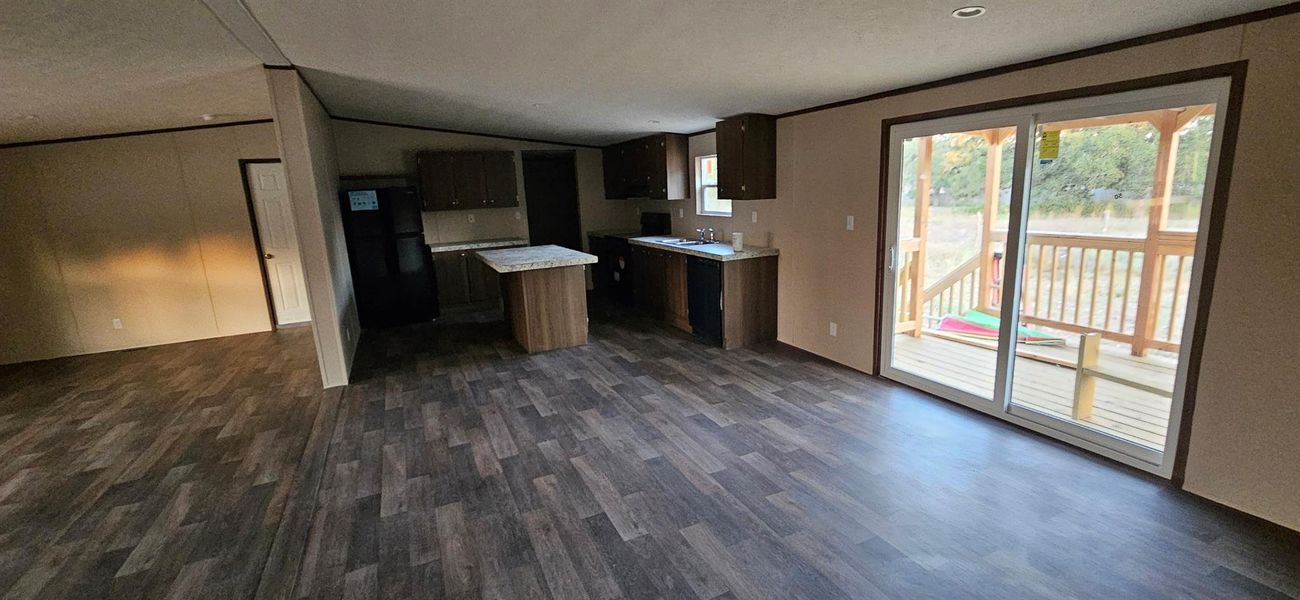 Spacious interior featuring wood-finish flooring, a kitchen island with stone-finish countertop, and dark wood cabinetry Spacious interior featuring wood-finish flooring, a kitchen island with stone-finish countertop, and dark wood cabinetry