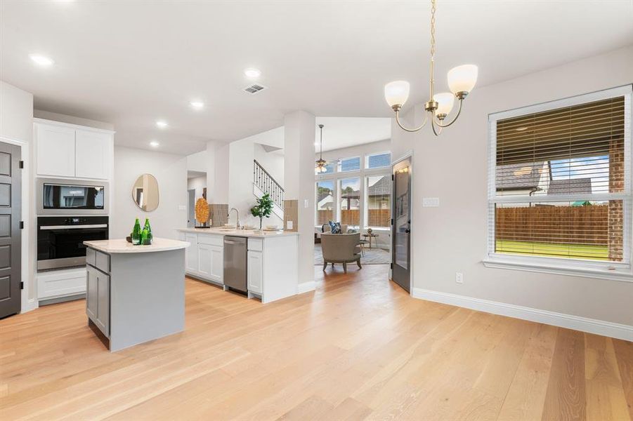 Kitchen featuring light hardwood / wood-style floors, white cabinetry, a kitchen island, and stainless steel appliances