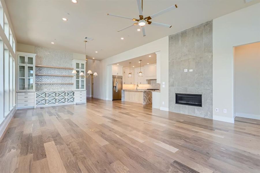 Unfurnished living room with ceiling fan, light wood-type flooring, and a tile fireplace