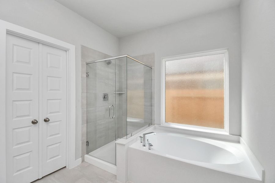 Indulge in a spa-like retreat within the confines of this primary bathroom. Delight in a spacious walk-in shower enveloped in stylish tile surround and unwind in a separate garden tub adorned with custom detailing. Sample photo of completed home with similar floor plan. Actual colors and selections may vary. Indulge in a spa-like retreat within the confines of this primary bathroom. Delight in a spacious walk-in shower enveloped in stylish tile surround and unwind in a separate garden tub adorned with custom detailing. Sample photo of completed home with similar floor plan. Actual colors and selections may vary.