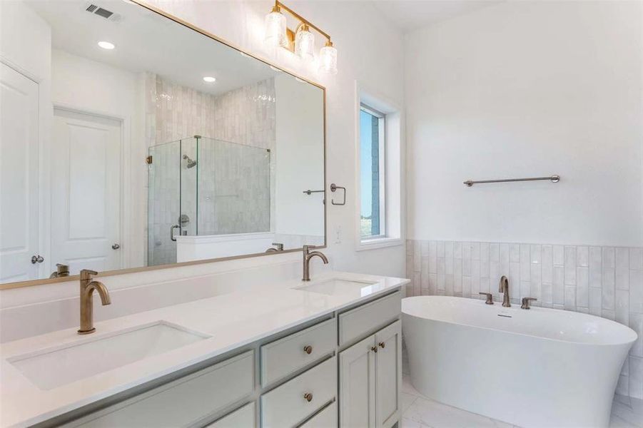 Full bath with a shower stall, a freestanding tub, double vanity, tile walls, and wainscoting