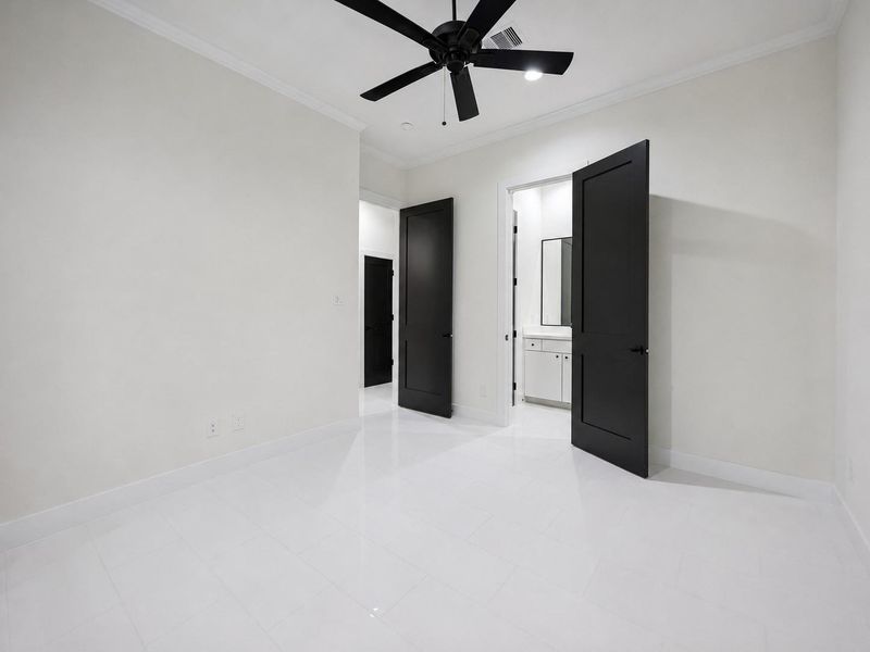 Another view of the bedroom highlights its crisp modern palette and direct connection to the adjoining bathroom. Large-format tile flooring creates a sleek foundation, while black interior doors and a contemporary ceiling fan add dramatic contrast. The generous proportions allow for a complete bedroom suite, additional seating, or flexible use as a private office or guest space. Another view of the bedroom highlights its crisp modern palette and direct connection to the adjoining bathroom. Large-format tile flooring creates a sleek foundation, while black interior doors and a contemporary ceiling fan add dramatic contrast. The generous proportions allow for a complete bedroom suite, additional seating, or flexible use as a private office or guest space.
