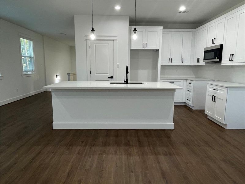 Kitchen with dark wood-type flooring, decorative light fixtures, white cabinets, and recessed lighting Kitchen with dark wood-type flooring, decorative light fixtures, white cabinets, and recessed lighting