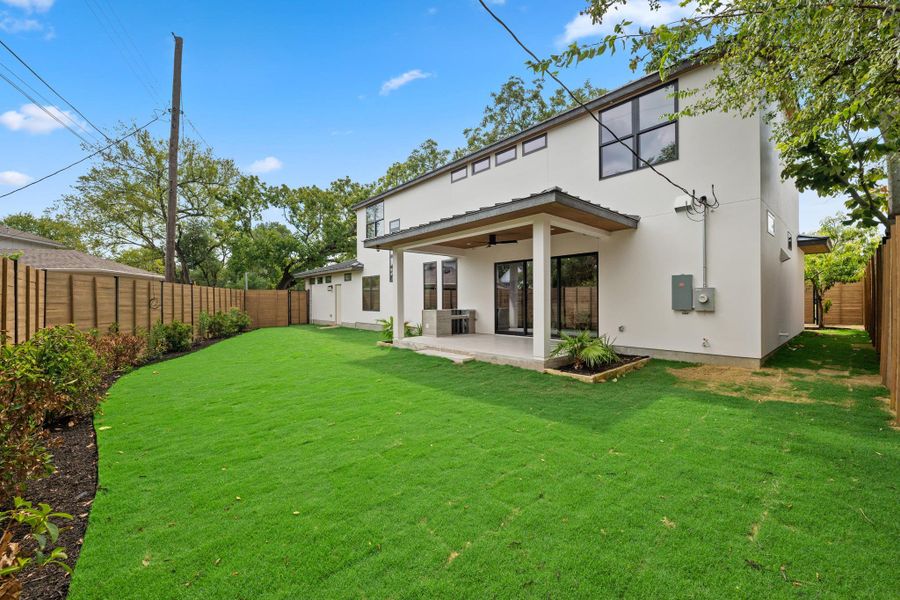 A spacious green lawn meets a covered patio ideal for outdoor relaxation.
