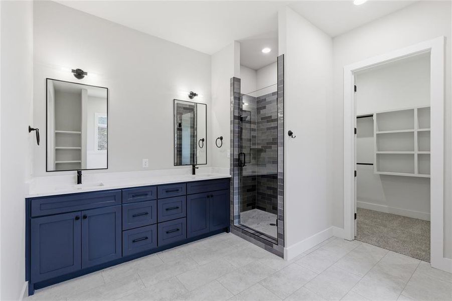 Bathroom featuring a dual vanity with navy cabinetry, matte black hardware, and rectangular mirrors