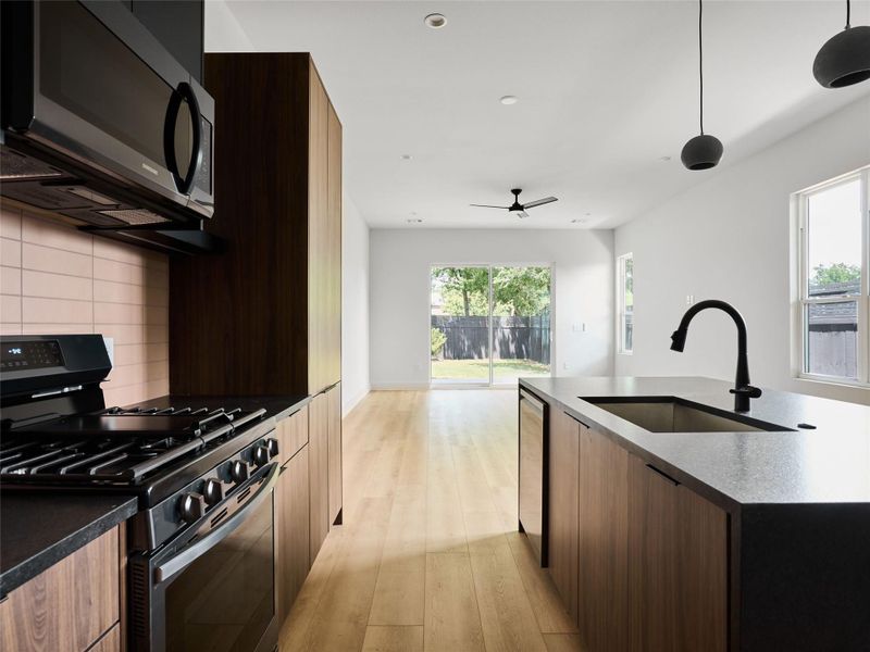 Kitchen with range with gas cooktop, black microwave, modern cabinets, decorative light fixtures, and recessed lighting Kitchen with range with gas cooktop, black microwave, modern cabinets, decorative light fixtures, and recessed lighting