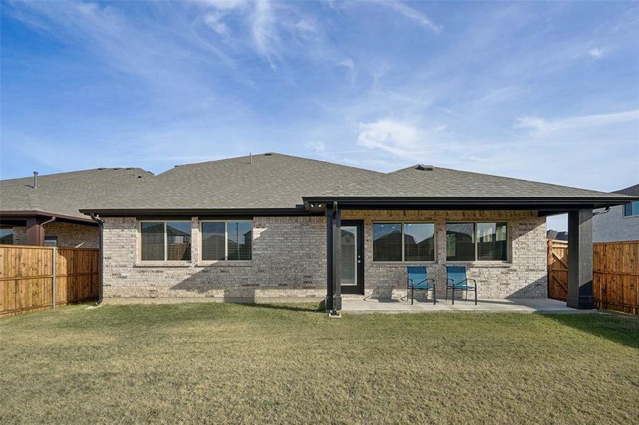 Back of house with a lawn and a patio