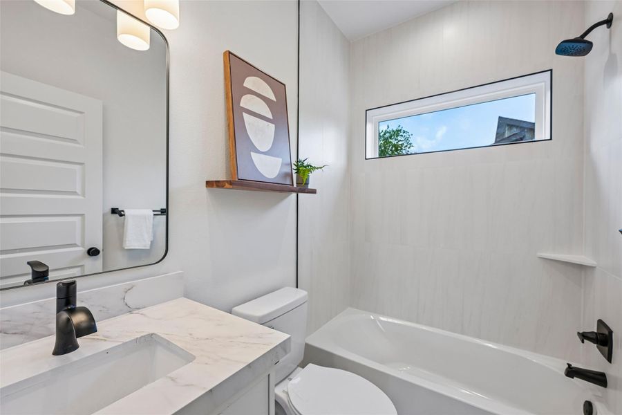 A well-lit bathroom features a fixed window and bathtub/shower combo.
