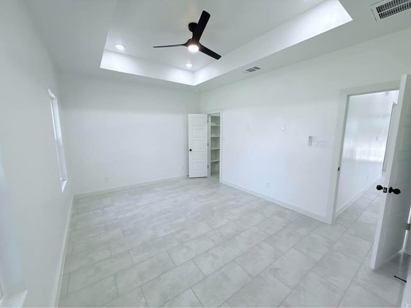 Unfurnished bedroom with a tray ceiling, a spacious closet, ceiling fan, and recessed lighting Unfurnished bedroom with a tray ceiling, a spacious closet, ceiling fan, and recessed lighting