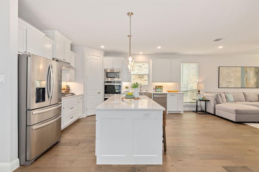 Kitchen with white cabinetry, large island, double ovens, gas cooktop and apron sink