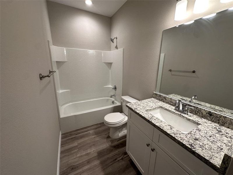 Full bathroom featuring vanity, toilet,  shower combination, and hardwood / wood-style flooring