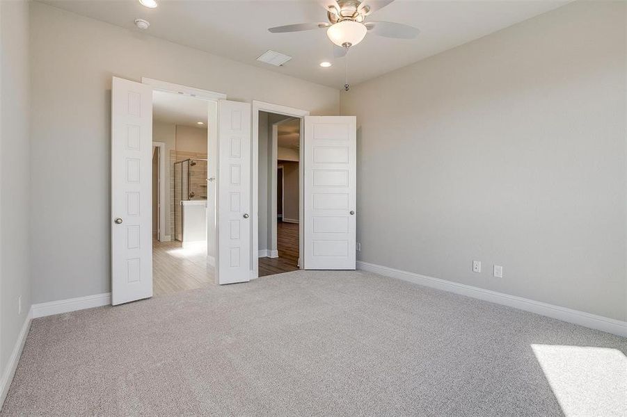 Unfurnished bedroom with light colored carpet and ceiling fan