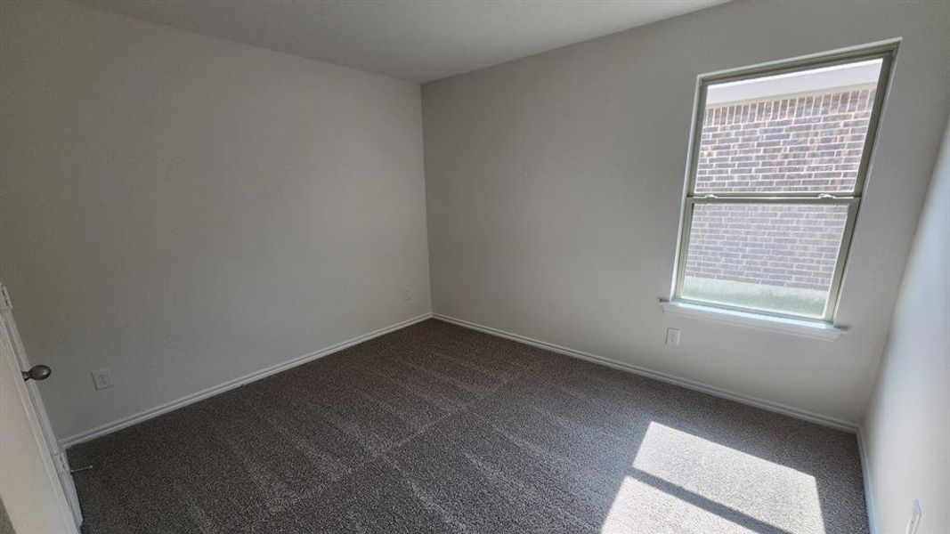 Bedroom featuring neutral wall paint, gray patterned carpeting, a single window with white trim, and a white baseboard