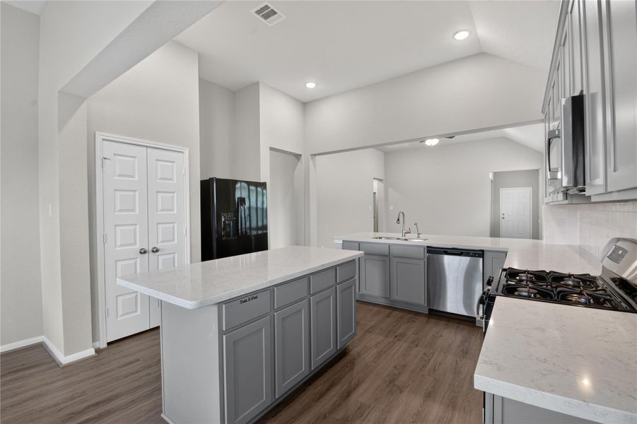 This modern kitchen features sleek gray cabinets and a spacious layout with ample natural light from large windows. The design includes a central island with a double sink and plenty of countertop space for cooking and entertaining. This modern kitchen features sleek gray cabinets and a spacious layout with ample natural light from large windows. The design includes a central island with a double sink and plenty of countertop space for cooking and entertaining.