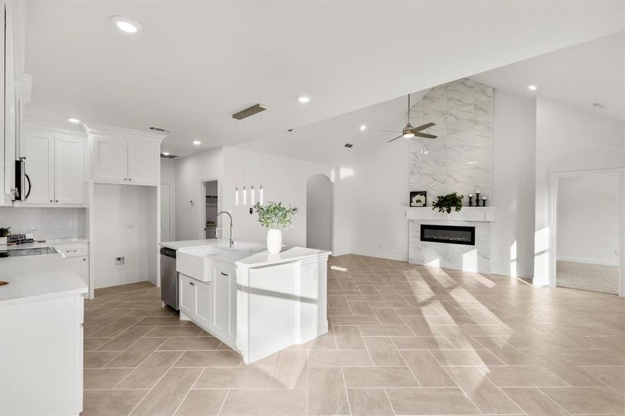 Kitchen featuring appliances with stainless steel finishes, sink, an island with sink, a high end fireplace, and white cabinets