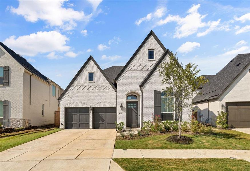 French country style house with brick siding, a garage, concrete driveway, and a front lawn French country style house with brick siding, a garage, concrete driveway, and a front lawn