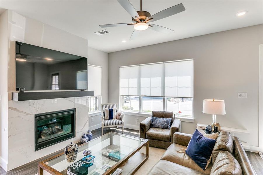 Living room featuring ceiling fan, a fireplace, and light hardwood / wood-style flooring