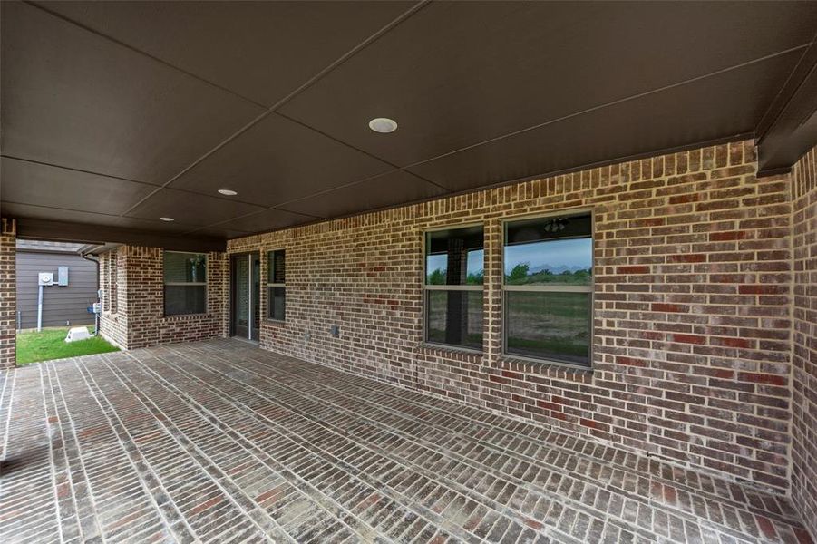 Covered outdoor patio featuring brick flooring, recessed lighting, and a dark ceiling