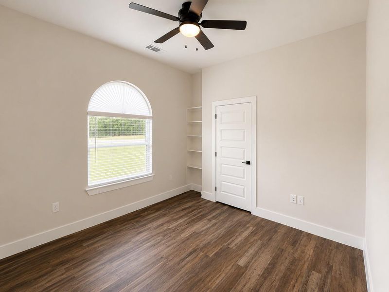 A quiet secondary room offering built-in shelving and an arched window.