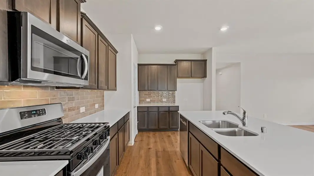 Modern kitchen featuring dark wood cabinetry, stainless steel appliances, and a gas range Modern kitchen featuring dark wood cabinetry, stainless steel appliances, and a gas range