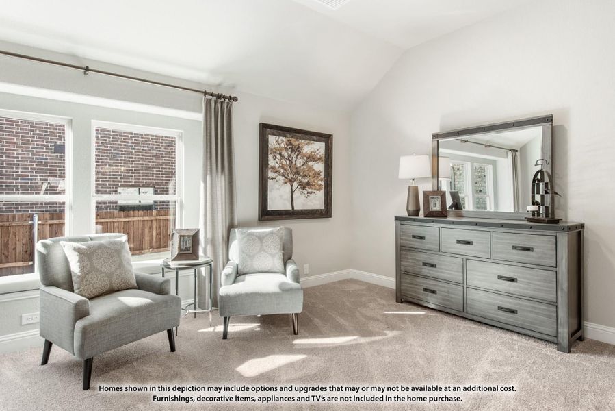 Bedroom sitting area with two gray armchairs, dresser with mirror, vaulted ceiling, and carpet flooring
