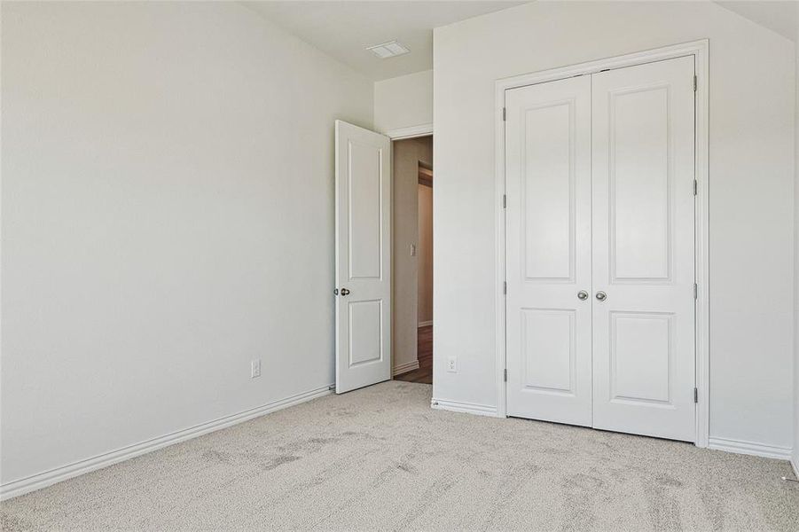 Unfurnished bedroom with light colored carpet and a closet