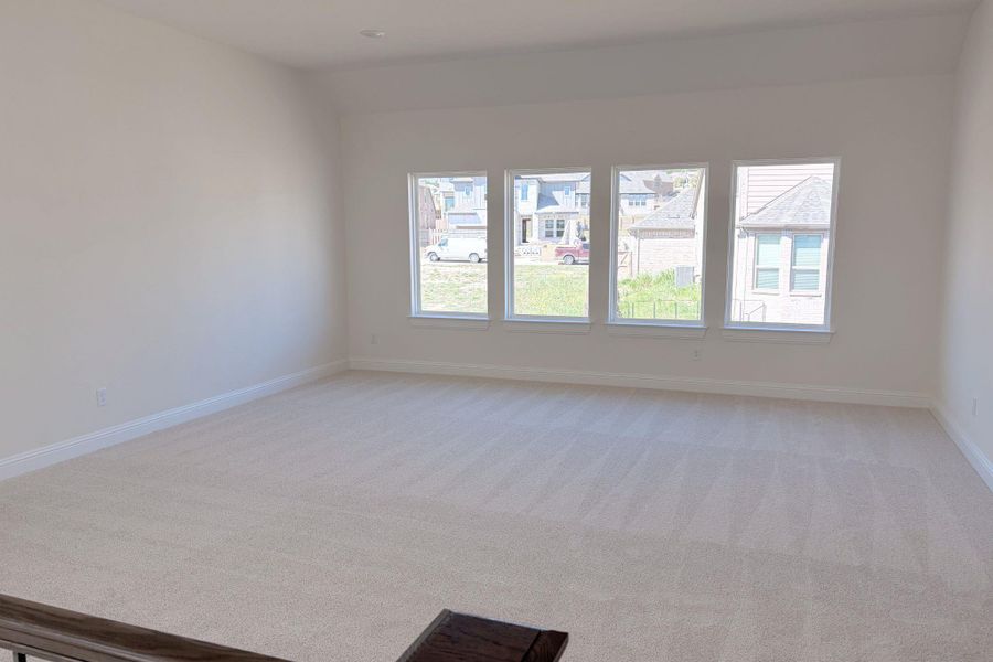 Unfurnished room featuring healthy amount of natural light, light carpet, and lofted ceiling