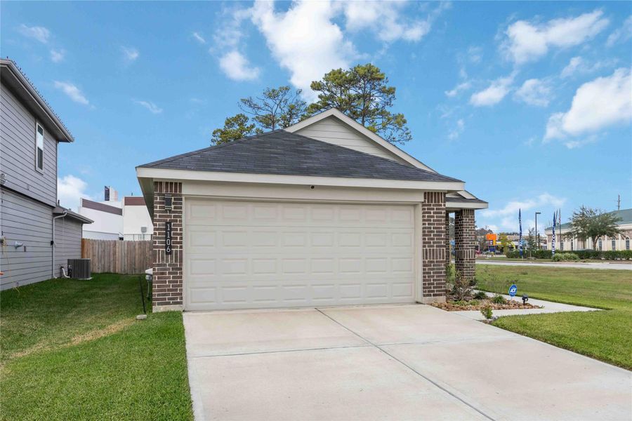 This photo shows a modern, single-story home with a brick exterior and a two-car garage.