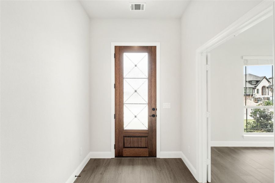 Entryway with dark wood front door featuring glass panel inserts and hardwood floors Entryway with dark wood front door featuring glass panel inserts and hardwood floors