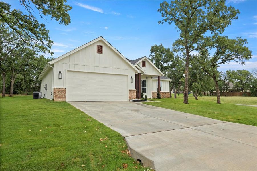Contemporary white board-and-batten exterior with a two-car garage, brick accents, and a concrete driveway Contemporary white board-and-batten exterior with a two-car garage, brick accents, and a concrete driveway