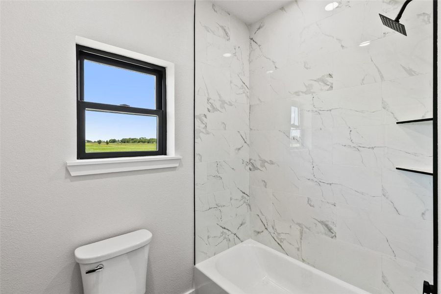 Thoughtfully designed guest bathroom featuring a floating double vanity, illuminated mirror, and a separate tub/shower and water closet area for added comfort and convenience.